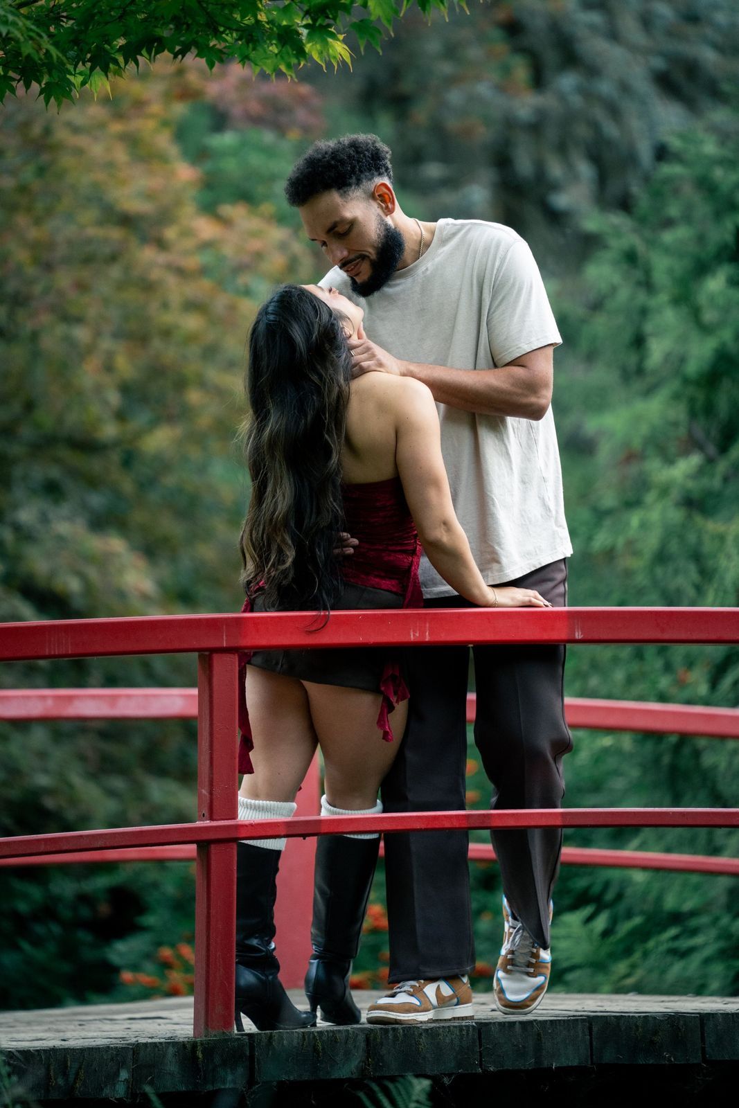 Couple kissing on a red garden bridge